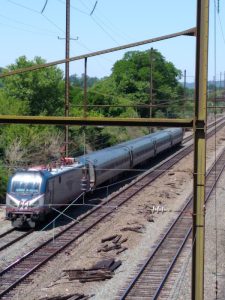 An Amtrak train engine pulling four passenger cars.